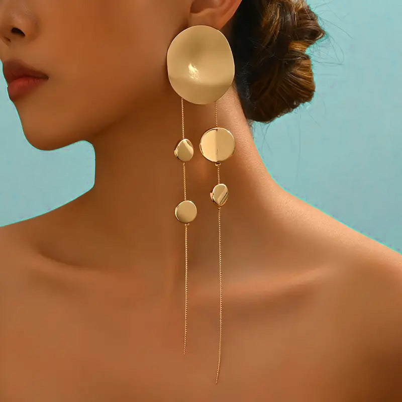 Close-up of a person wearing gold earrings with a blue background