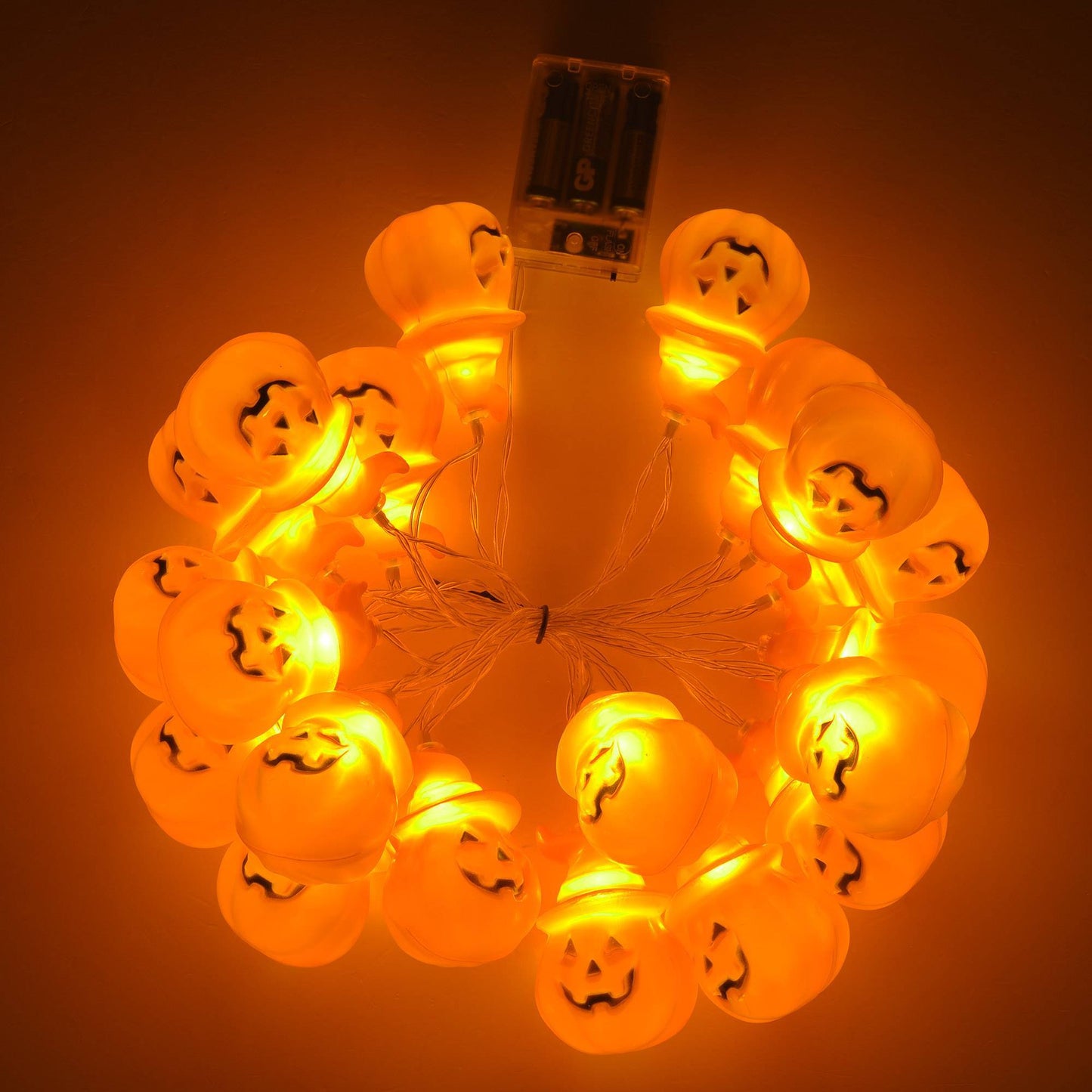Halloween-themed string lights with jack-o'-lantern faces on an orange background