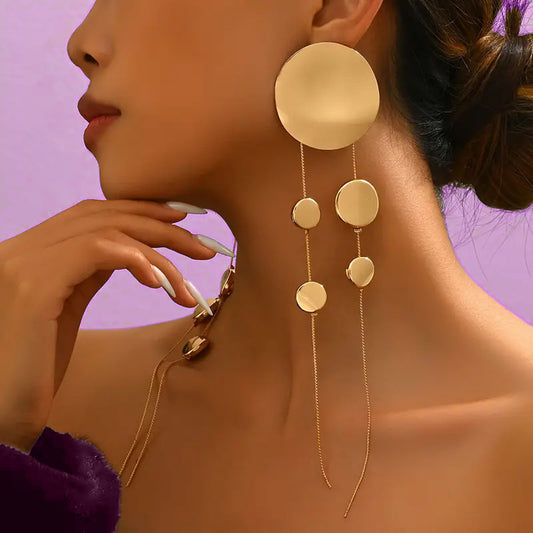 Close-up of a woman wearing gold earrings with a purple background